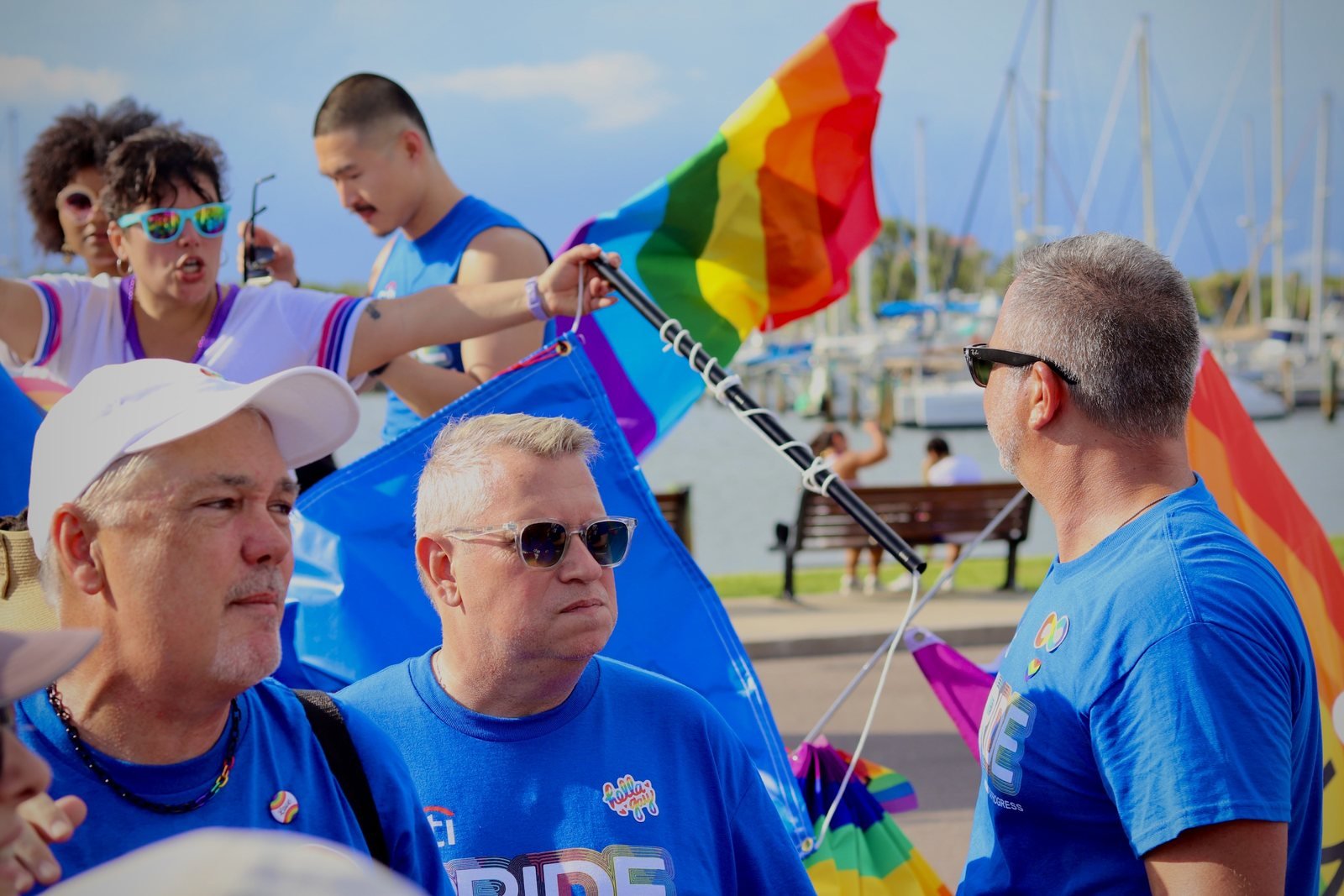 Marchers raising a rainbow flag beside the marina