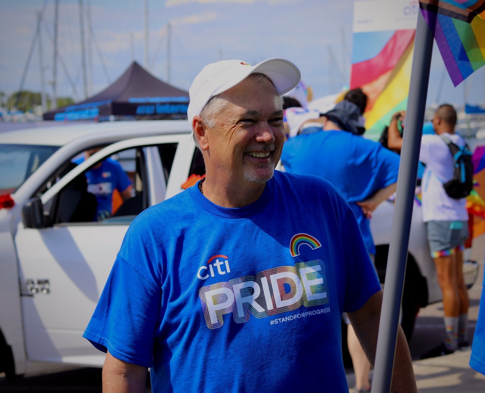 Smiling man in a white cap and blue Pride shirt