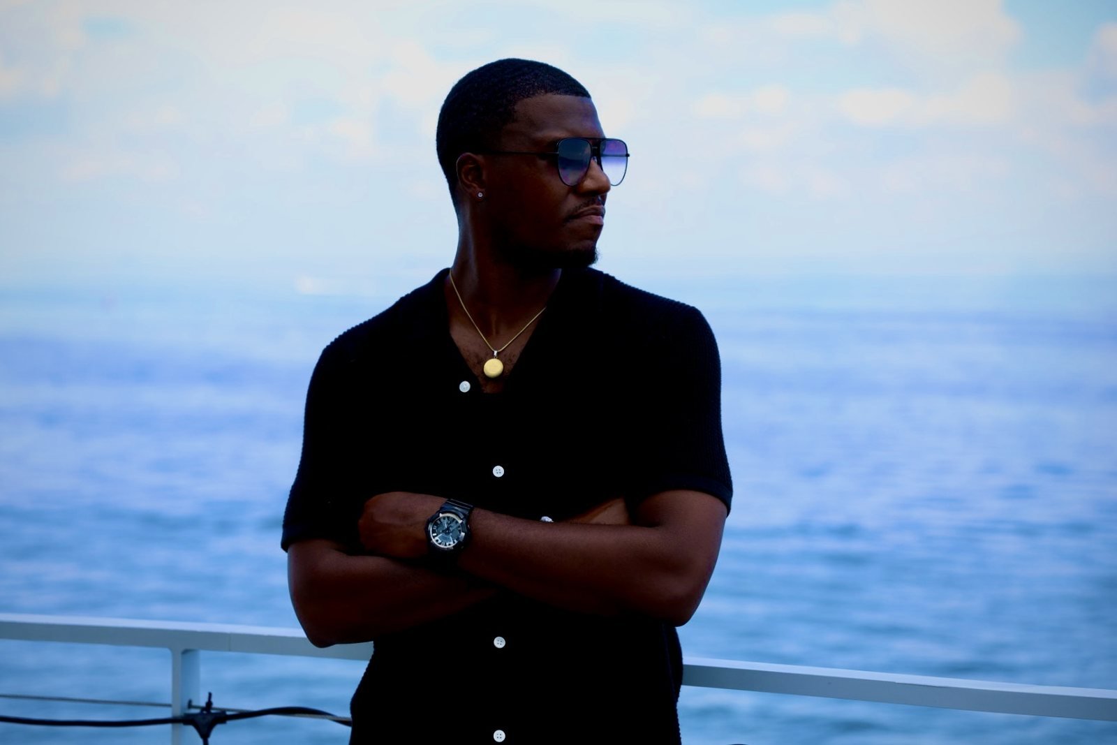 Man in a black shirt and sunglasses beside the ocean