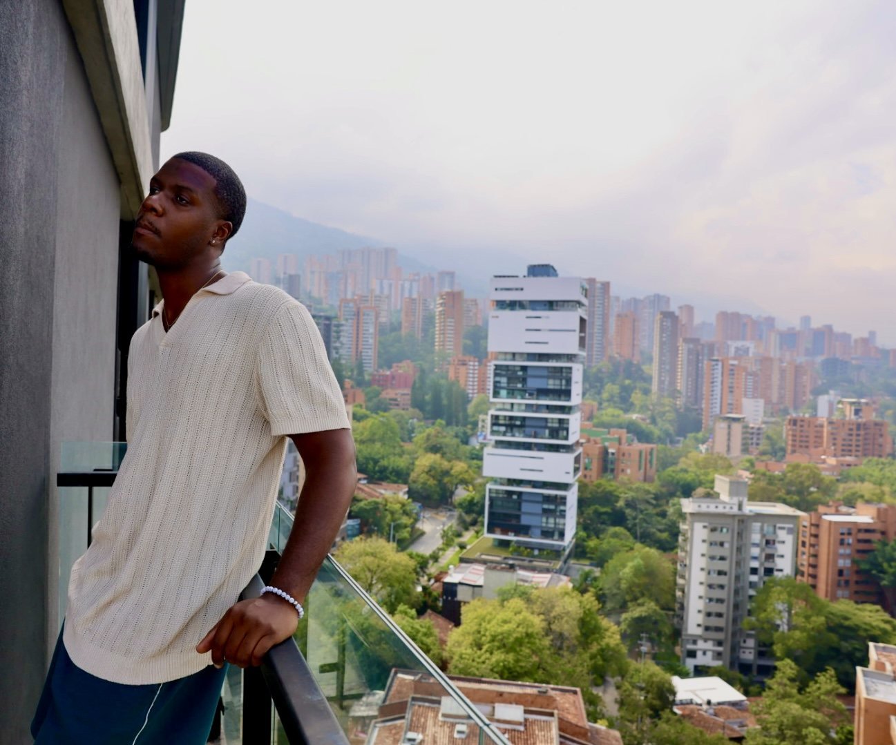 Man in a white shirt on a balcony overlooking the city
