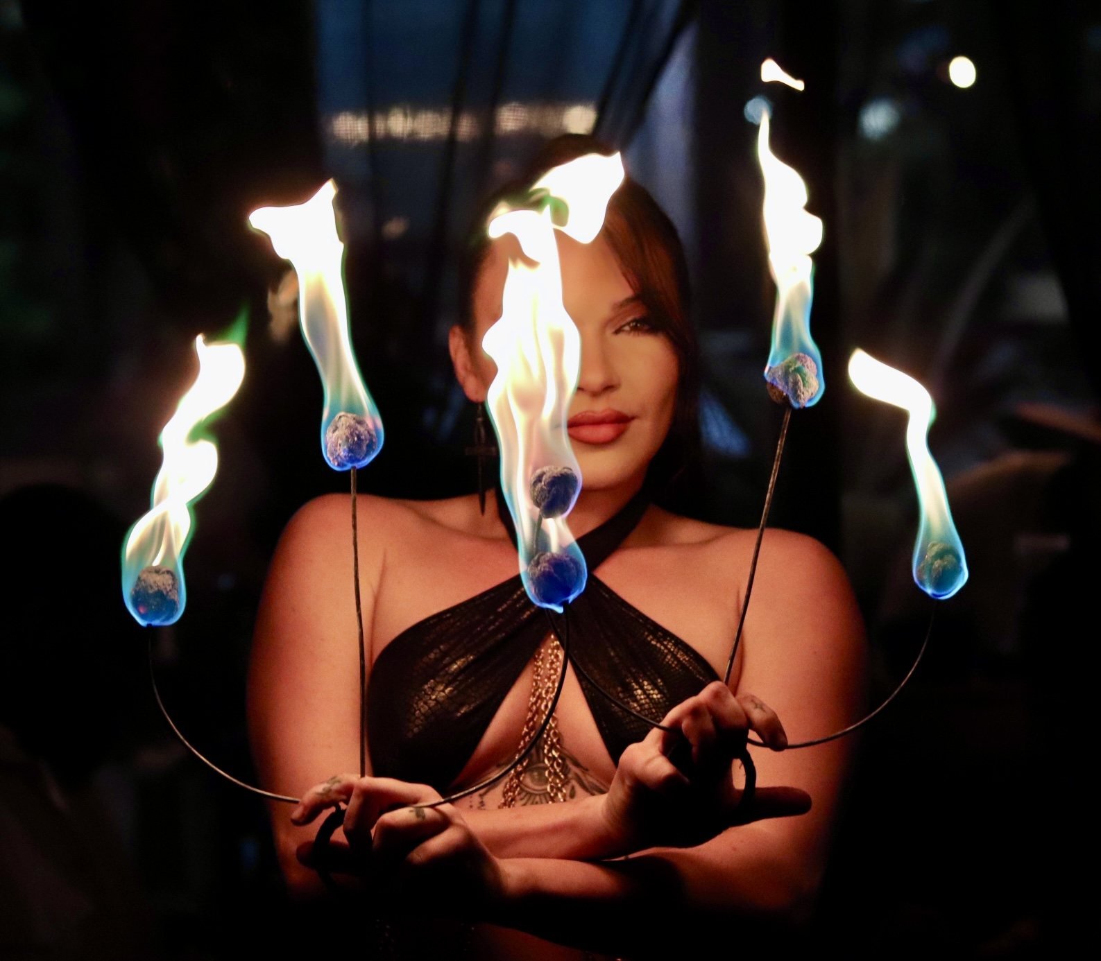 Woman framed by small flames in a dark portrait