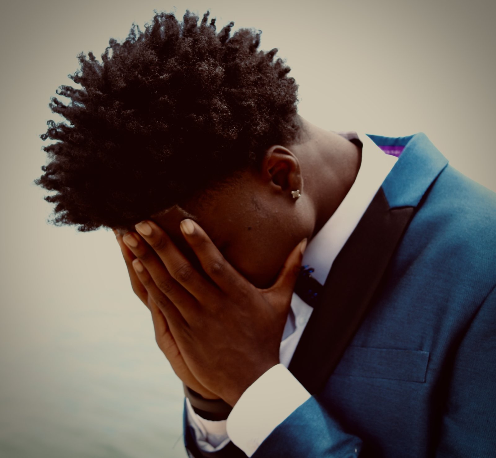 Man in a blue suit with his head bowed